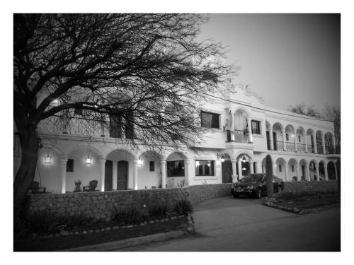 a large white house with a car parked in front of it at Hotel Portal del Santo in Cafayate