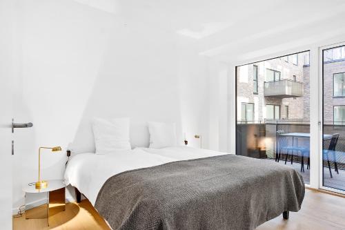 a white bedroom with a bed and a large window at STAY Seaport in Copenhagen