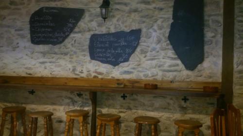 a bar with stools in front of a stone wall at Hotel Rural Grado del Pico in Grado del Pico