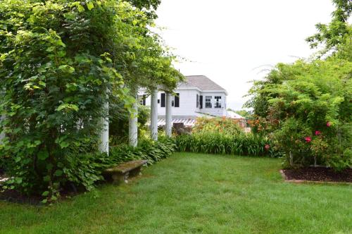 a yard with a white house and some bushes at The Brewster Inn in Dexter