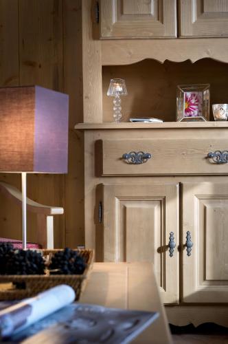 a room with a table with a lamp and a cabinet at CGH Résidences & Spas Orée Des Cimes in Peisey-Nancroix