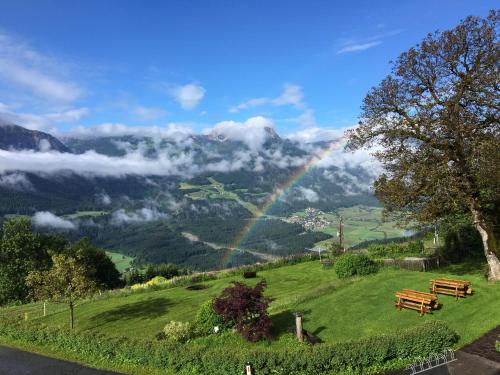 a rainbow over a green field with benches on a hill at Mösslacher's Ferienwohnungen in Hermagor