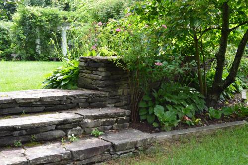 a stone retaining wall with a tree in a garden at The Brewster Inn in Dexter