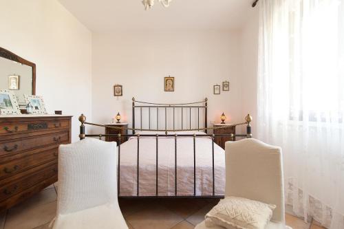 a bedroom with a bed and two white chairs at Villa Rose in Marina di Mancaversa