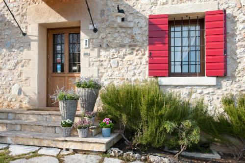 a house with red shutters and potted plants on the stairs at Agriturismo Prime Gemme in Nervesa della Battaglia