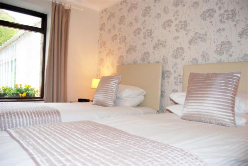 two beds in a hotel room with a window at Kingswood Hotel in Burntisland
