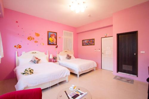 a pink bedroom with two beds and a table at Vicking Guesthouse in Taitung City