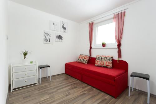 a living room with a red couch and a window at Lesní Penzion Vranov in Vranov nad Dyjí