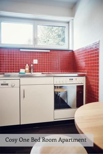a red tiled kitchen with a sink and a oven at Serviced Apartments by Solaria in Davos