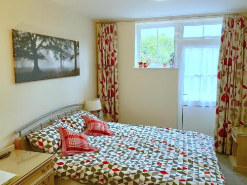 Un dormitorio con una cama con almohadas rojas y una ventana en High Banks studio, en Sevenoaks