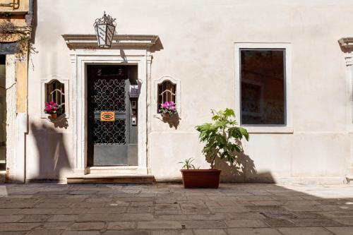 a white building with a door and a potted plant at Hotel San Samuele in Venice