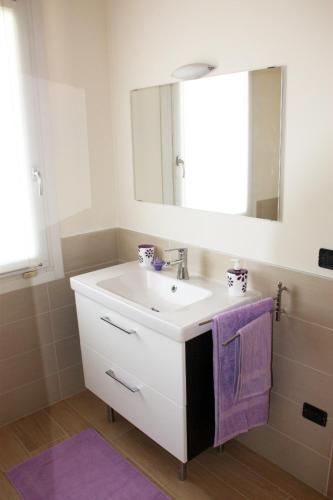 y baño con lavabo, espejo y toalla morada. en i mirtilli, en Pianezze