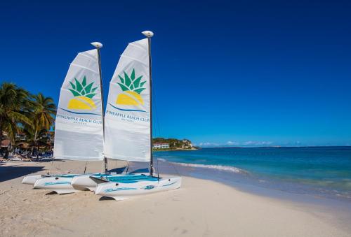 two sailboats on a beach with the ocean at Pineapple Beach Club - All Inclusive - Adults Only in Willikies