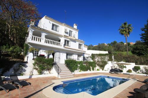 una gran casa blanca con piscina frente a ella en Villa La Recalada en Estepona