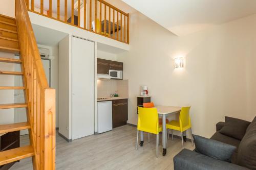 ein kleines Wohnzimmer mit einem Tisch und gelben Stühlen in der Unterkunft City Résidence Bordeaux Centre in Bordeaux