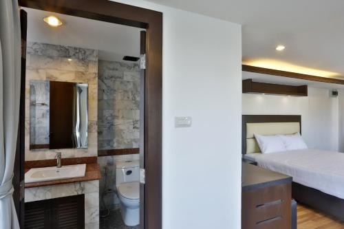 a bedroom with a bed and a bathroom with a sink at Initial Hua Hin - SHA Plus in Hua Hin
