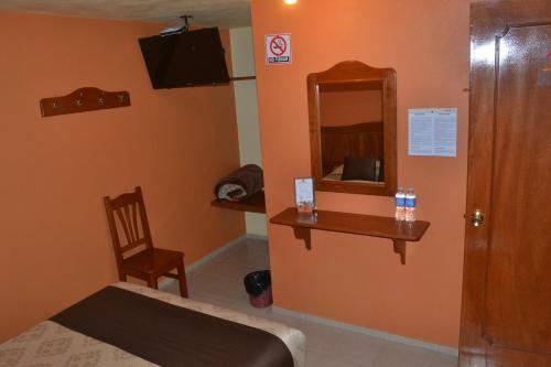 Habitación con cama, espejo y silla. en Hotel Márquez, en Chignahuapan