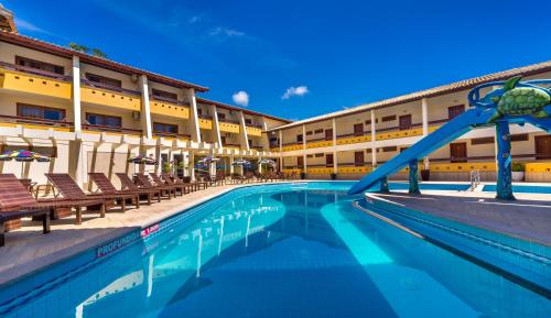 a pool in front of a hotel with a slide at Porto Cálem Praia Hotel in Porto Seguro