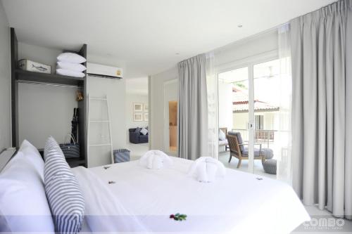 a bedroom with a large white bed and a living room at Combo Beach Hotel Samui in Chaweng