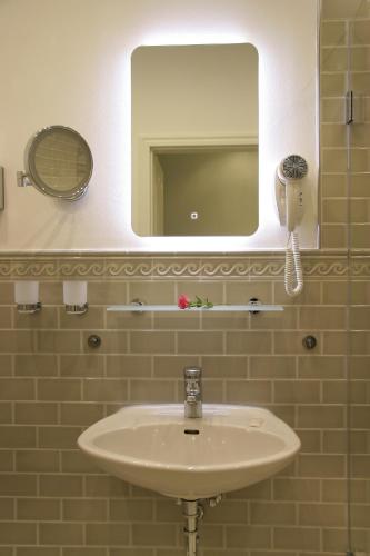 a white sink in a bathroom with a mirror at Hotel Verdi in Rostock