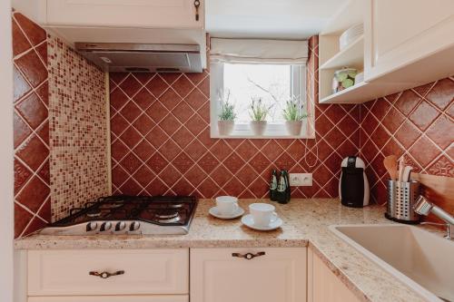 uma cozinha com paredes de azulejos vermelhos e um fogão em Apartament Wisniowa em Varsóvia