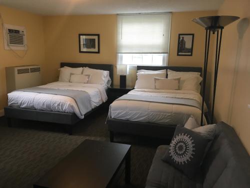 Clarence Inn Extended Stay في Clarence Center: غرفة فندقية بسريرين واريكة