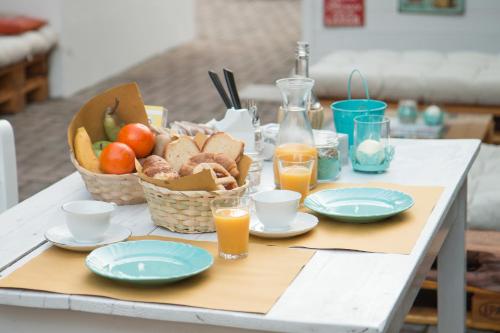 un tavolo con un cesto di frutta, piatti e succo d'arancia di Hotel Villa Cesare B&B ad Alba Adriatica