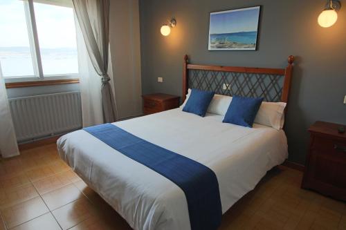 um quarto com uma cama grande e almofadas azuis em Hotel Alda Bueumar em Bueu