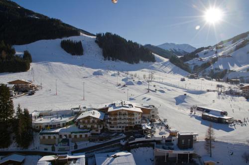 a ski lodge on a snowy mountain with the sun in the sky at Wellness- und Familienhotel Egger in Saalbach-Hinterglemm