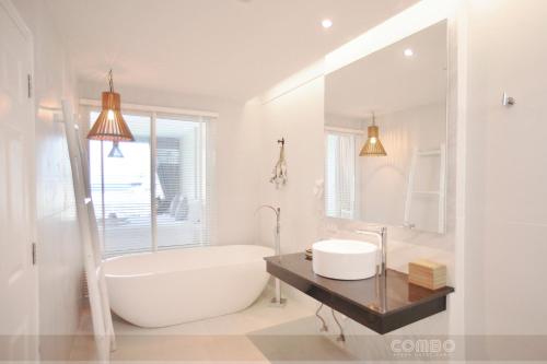 La salle de bains blanche est pourvue d'une baignoire et d'un lavabo. dans l'établissement Combo Beach Hotel Samui, à Chaweng