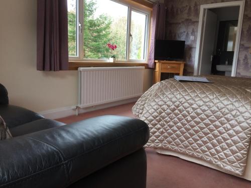 a bedroom with a couch and a bed and a window at Torbeag House in Fort William