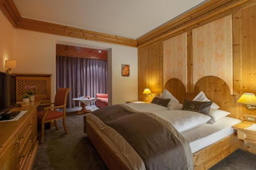 a bedroom with a bed and a desk and a television at Der Verdinser Hof in Schenna