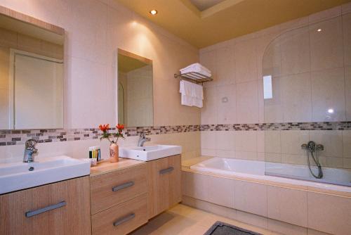 a bathroom with two sinks and a tub and a sink and mirror at Lemnos Village Resort Hotel in Platy
