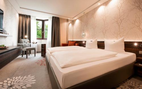 a bedroom with a large white bed and a desk at Land & Golf Hotel Stromberg in Stromberg