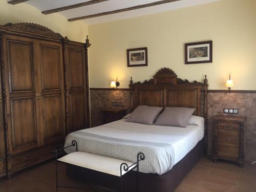 een slaapkamer met een bed en een houten kast bij Casa Rivera Río Jucar in Valdeganga