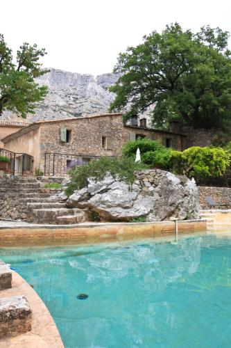 une piscine d'eau bleue devant un bâtiment dans l'établissement Le Moulin en Provence, à Saint-Antonin-sur-Bayons