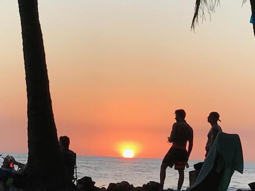 a group of people standing on the beach watching the sunset at Hotel Beachfront Vista Hermosa in Jacó