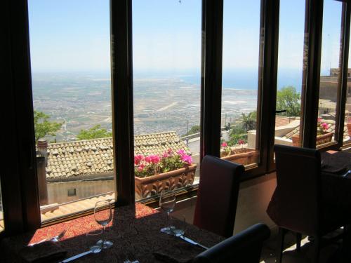 a dining room with a table and chairs and windows at Hotel Elimo in Erice