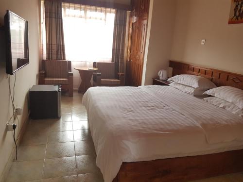 Un dormitorio con una gran cama blanca y una ventana en China Garden, en Nairobi