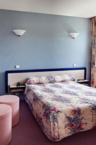 a bedroom with a bed with a floral bedspread at Hôtel du Lac in Lacapelle-Viescamp