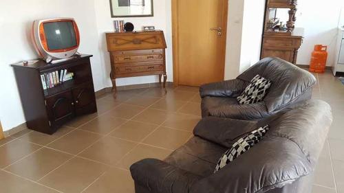 sala de estar con sofá de cuero y TV en Ti Marquitas, en Vila de Rei