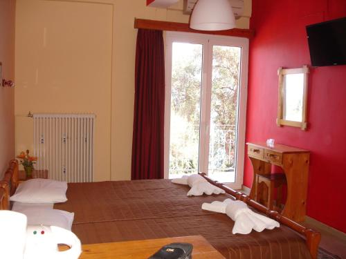 Zimmer mit einem Bett mit roten Wänden und einem Fenster in der Unterkunft Panorama in Perama