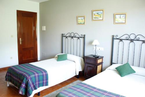 a bedroom with two beds and a table with a lamp at Pensión Mosende in Porriño