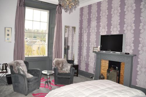 a bedroom with a bed and a tv and a fireplace at The Bank Guest House in Hawick