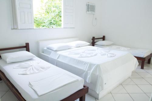 3 camas en una habitación blanca con ventana en Pousada Valmar, en Aracaju