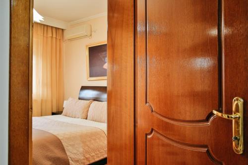 a door leading to a bedroom with a bed at Gold Hotel in Korçë