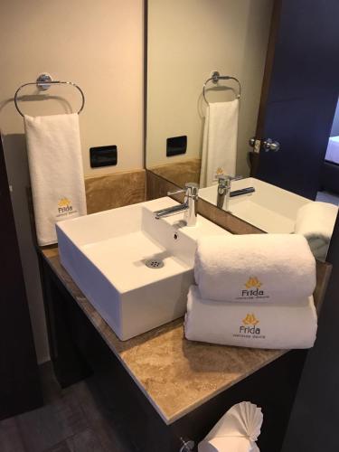 a bathroom with a white sink and towels on a counter at Hotel Frida in Puebla
