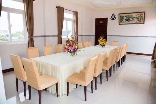 una gran mesa blanca con sillas y flores. en Hoa An Hotel, en Rạch Giá