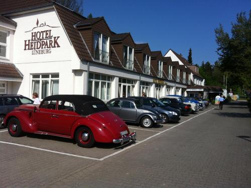 a row of cars parked in a parking lot in front of a building at Hotel Heidpark in Lüneburg