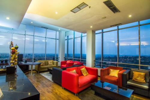 a living room with couches and tables and windows at Grand Candi Hotel in Semarang